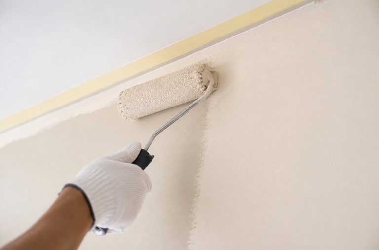 Pintor profesional aplicando con rodillo una pared interior protegida con cinta de carrocero en una vivienda de Tarragona