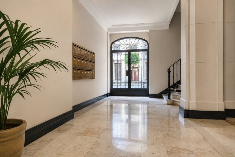 Vestíbulo elegante de edificio residencial restaurado con paredes claras y zócalo antracita