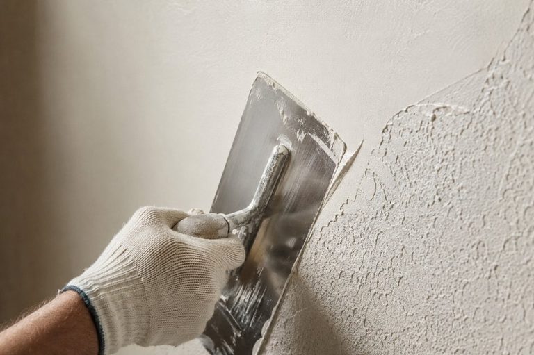 Aplicación de masilla con llana de acero sobre una pared para alisarla tras retirar el gotelé